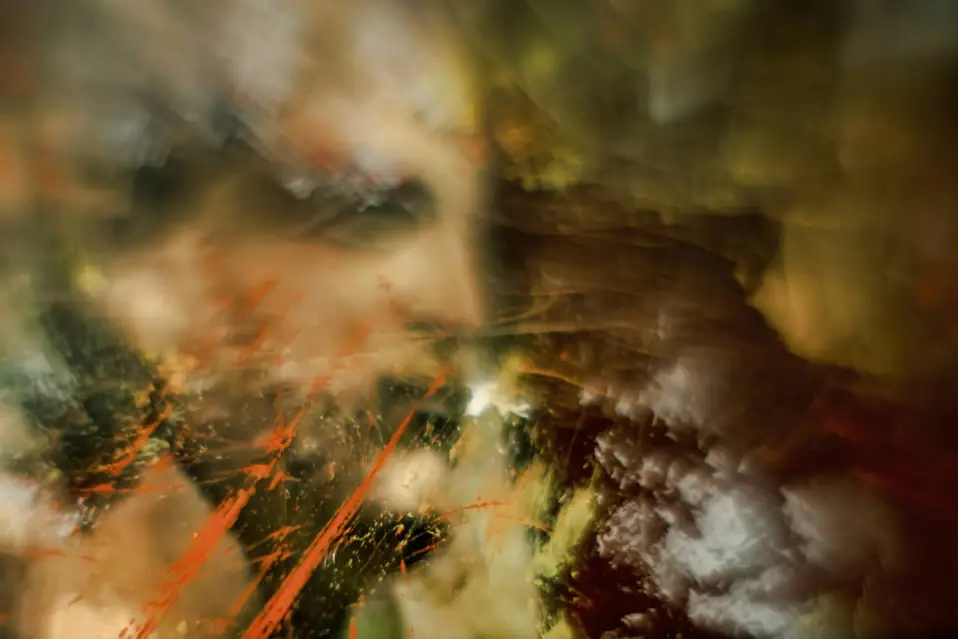Blurred mesh of warm light and orange streaks, suggesting Shop Pay identity linking crossing a UCP checkout handoff