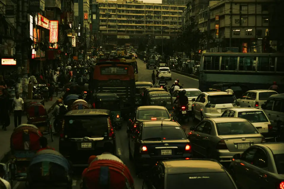 Evening traffic jam packed with rickshaws, cars, buses, and red brake lights on a dense urban street