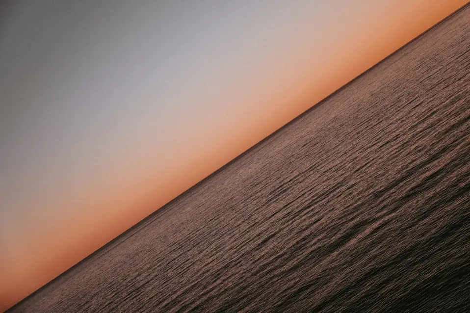 Calm horizon where dark water meets a pale sky, suggesting the £135 UK VAT threshold Shopify Tax now draws from fulfilment location